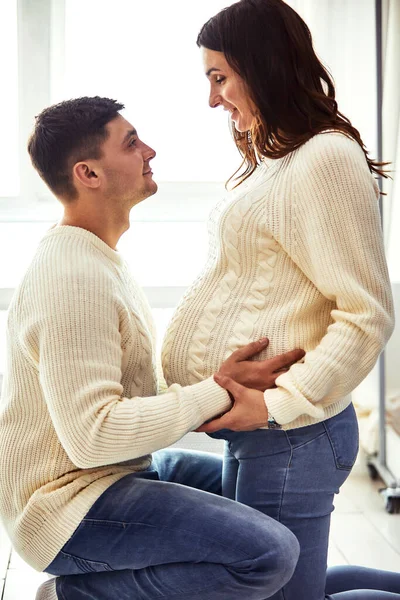 De cerca retrato de pareja adolescente esperando riendo felizmente, abrazando al bebé en el vientre juntos. Pareja vestida en colores azul y blanco . — Foto de Stock