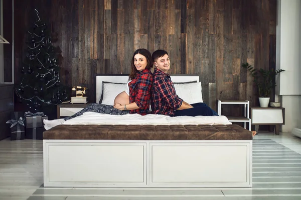 Feliz familia embarazada se encuentra en la cama de la casa. — Foto de Stock