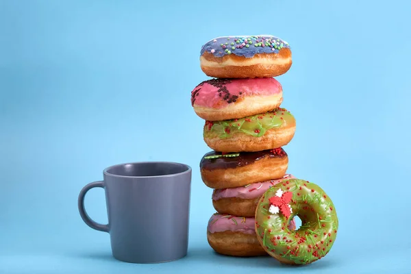 Ein Stapel Donuts mit einem blauen Becher auf blauem Hintergrund. Konzept Dessert, süßes Leben, wir sind, was wir essen. Blauer Hintergrund, Kopierraum. — Stockfoto