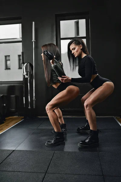 Całkowite ujęcie dwóch młodych kobiet w odzieży sportowej stojących razem na siłowni. Siostra w klubie zdrowia patrząc przed kamerą. — Zdjęcie stockowe