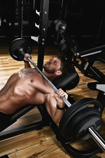 Ung muskulös man lyfta en skivstång bänk press i gymmet. Vacker kropp, mål prestation, Sport som en livsstil. — Stockfoto