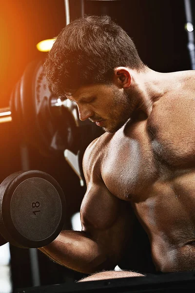 Vücut geliştiren kaslı adam spor salonunda dambıllarla egzersiz yapıyor. Atletik vücut, sağlıklı yaşam tarzı, spor motivasyonu, pozitif vücut.. — Stok fotoğraf