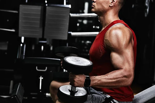 筋肉の男のボディビルダーは、ジムでダンベルのクローズアップで演習を行っています。運動体,健康的なライフスタイル,フィットネスの動機,正の体. — ストック写真