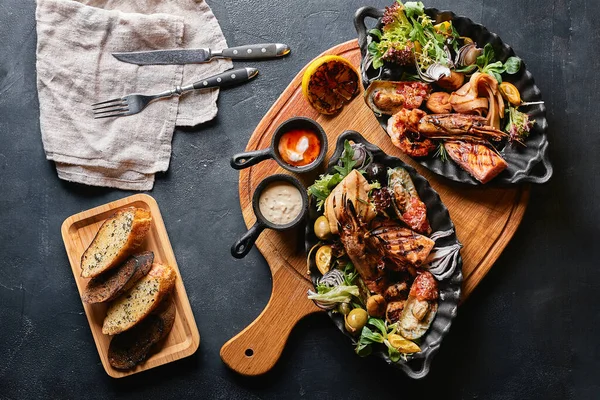 Surtido de mariscos en platos. Hermosa composición sobre una mesa de mariscos servida, calamares, camarones, filete de salmón y pulpo. Foto de comida, bajo perfil, cocina tradicional italiana. Vista superior, guardar el espacio — Foto de Stock