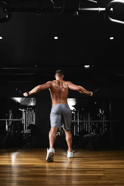 一个男人在体育馆里用模拟器锻炼他的胳膊和胸部，为不同的肌肉群做运动。发现动机，运动生活方式，健康，运动身体，身体积极。薄膜颗粒 — 图库照片