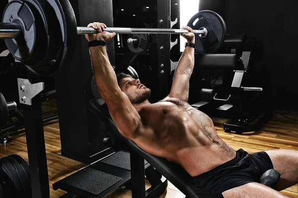 Guapo joven haciendo ejercicio de press de banca en el gimnasio, motivación fitness, estilo de vida deportivo, salud, cuerpo atlético, cuerpo positivo. Grano de película, enfoque selectivo —  Fotos de Stock