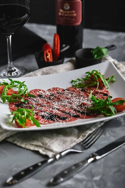 Beef carpaccio on a gray background. Set of carpaccio wine and cutlery, top view. gray background, copy space. — 스톡 사진
