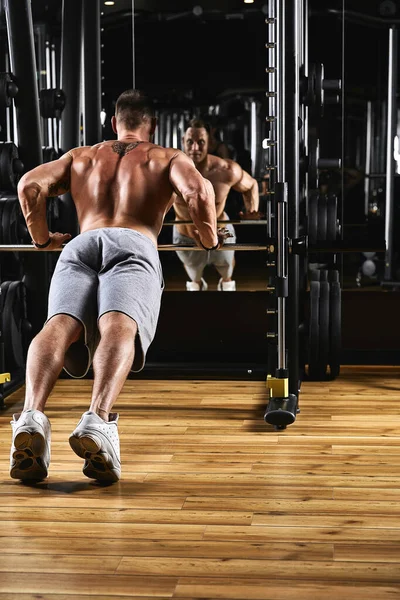 En man tränar sina armar och bröst i gymmet på simulatorn, gör övningar för olika muskelgrupper. Fintes motivation, sport livsstil, hälsa, atletisk kropp, kropp positiv. Filmkorn — Stockfoto