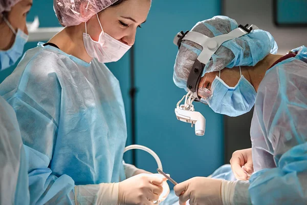 Surgical team in the operating room, close-up. An international team of professional doctors in a modern operating room is undergoing surgery. Saving lives, modern medicine, blue blue light — Stock Photo, Image