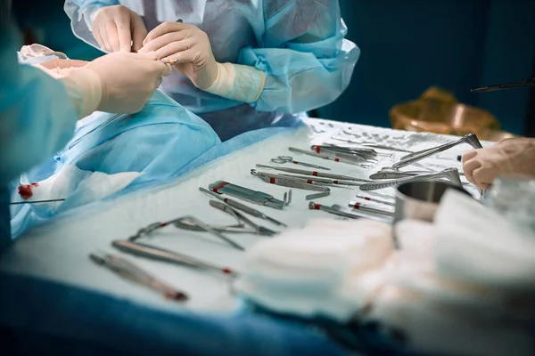 Die Hände des Chirurgen halten ein Operationswerkzeug im Operationssaal. Nahaufnahme, schönes Licht, moderne Medizin, Leben retten. — Stockfoto