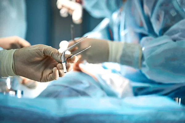 De chirurgen houden een operatietool vast in de operatiekamer. Close-up, mooi licht, moderne geneeskunde, Levens redden. — Stockfoto