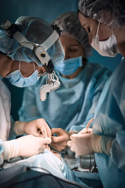 Hastanenin ameliyathanesinde. Profesyonel cerrah ve asistanlardan oluşan uluslararası bir ekip modern bir ameliyathanede çalışıyor. Profesyonel doktorlar kurtarılan hayatları başarıyla kutladılar. — Stok fotoğraf