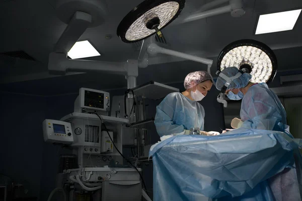 Na operačním sále nemocnice. Mezinárodní tým profesionálních chirurgů a asistentů pracuje v moderním operačním sále. Profesionální lékaři slaví úspěšně zachráněné životy. — Stock fotografie
