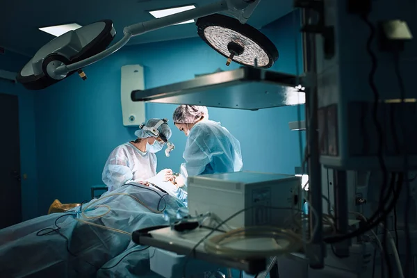 In the hospital operating room. An international team of professional surgeons and assistants works in a modern operating room. Professional doctors celebrate successfully saved lives.