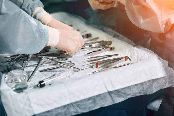 Las manos de los cirujanos sostienen una herramienta de operación en el quirófano. Primer plano, hermosa luz, medicina moderna, salvar vidas . — Foto de Stock