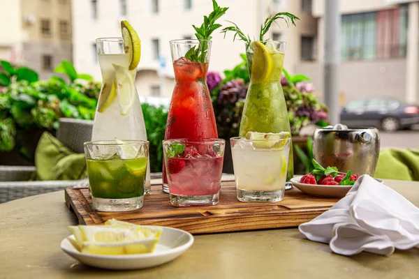 Refrescos de verano, un juego de limonadas. Limonadas en jarras sobre la mesa, cuyos ingredientes se preparan se disponen alrededor . — Foto de Stock