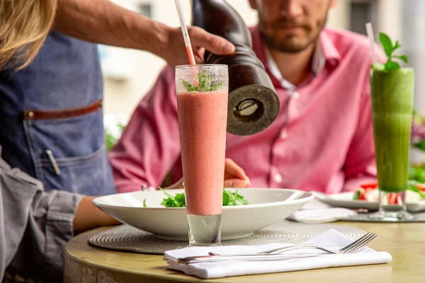 Concept restaurants, guest service. The waiter fills the salad with fresh pepper.