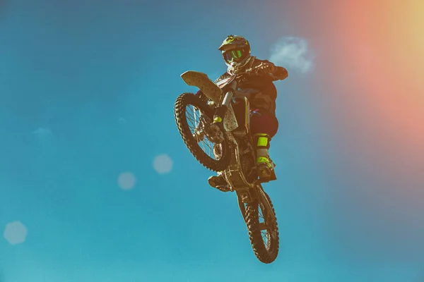El motociclista hace el truco y salta en el aire. Concepto extremo, adrenalina. Retroiluminación especial, grano de película. Copiar espacio. Fondo del cielo —  Fotos de Stock
