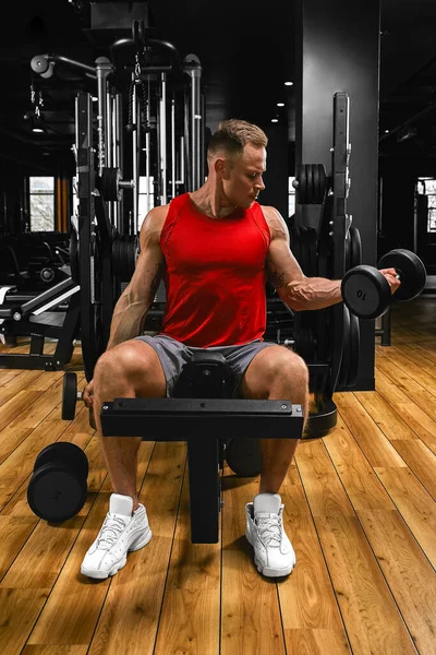 Een shirtloze gespierde man doet biceps oefeningen met halter oefeningen als onderdeel van zijn bodybuilding workout. Fitness motivatie, sport lifestyle, gezondheid, atletisch lichaam, lichaam positief. Filmgraan — Stockfoto