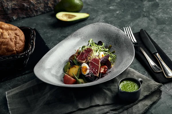 Nikoise-Salat mit Thunfisch auf einem grauen Teller, auf einem Serviertisch. Ein schönes Gericht vom Koch, Lebensmittel Foto, grauer Hintergrund, Kopierraum, traditionelle französische Küche. — Stockfoto