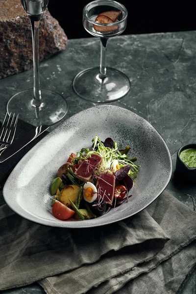 회색 접시 위에 참치와 함께 먹는 니 커즈 샐러드 . 식탁 위에요. 요리사의 아름다운 요리, 음식 사진, 회색 배경, 복사 공간, 전통적 인 프랑스 요리. — 스톡 사진