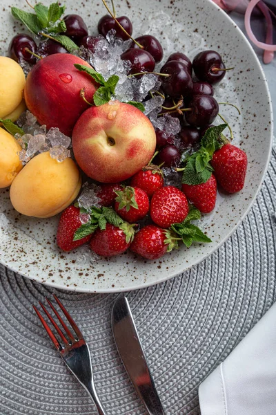 Zdravý ovocný talíř, jahody, jablka, broskve, meruňky na tmavě šedém dřevěném stole, výhled shora, detailní záběr, selektivní ostření. — Stock fotografie
