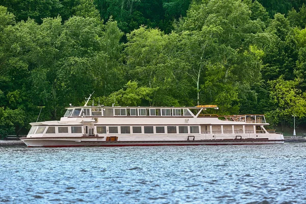 Un bateau fluvial moderne flotte dans le contexte du panorama de la ville, parcs modernes. Architecture urbaine moderne pittoresque. Tourisme, repos en ville, transport fluvial . — Photo