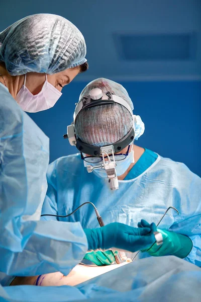 Close up portrait of female surgeon doctor wearing protective mask and hat during the operation. Healthcare, medical education, surgery concept. — Stock Photo, Image