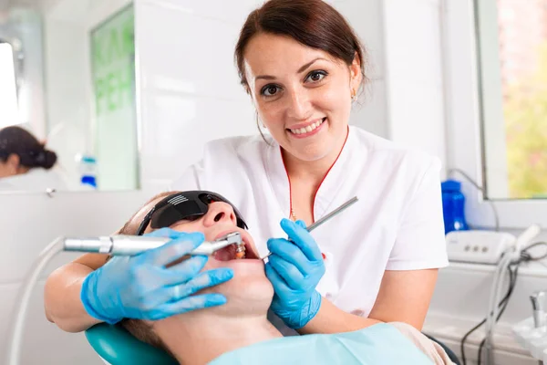 Odontologia, dentista trata um dente para um paciente do sexo masculino. Remoção de cárie, instalação de recheios nos dentes . — Fotografia de Stock