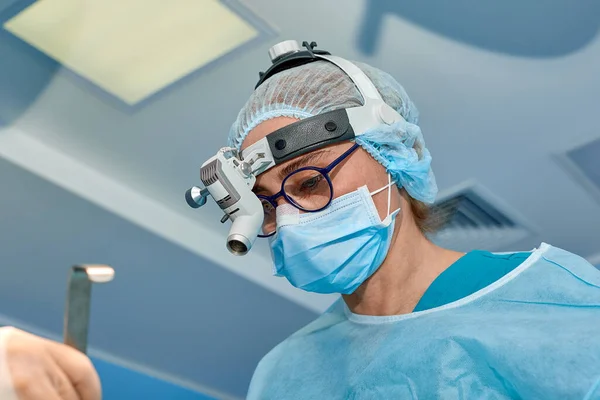 Närbild porträtt av kvinnliga kirurgen läkare bär skyddande mask och hatt under operationen. Sjukvård, medicinsk utbildning, kirurgi koncept. — Stockfoto