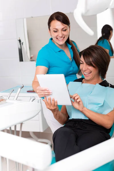 Zahnärztin zeigt Zähne auf digitalem Tablet-Bildschirm. Patient sitzt auf Stuhl in professioneller Zahnklinik — Stockfoto