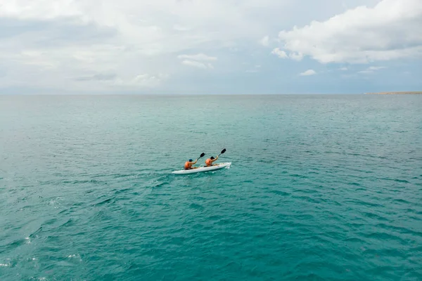 Kayak en el mar desde la vista trasera. Pareja feliz kayak a lo largo del horizonte con hermosas nubes. Viajar, nuevos horizontes, sed de descubrimientos, descanso activo . — Foto de Stock