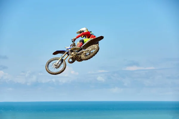 Biker does the trick and jumps in the air. Extreme concept, adrenaline. Copy space. Sky background