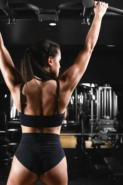 Mujer haciendo ejercicio en el gimnasio - pull ups. Imagen cruzada procesada, contrastante, imagen granulada oscura . —  Fotos de Stock