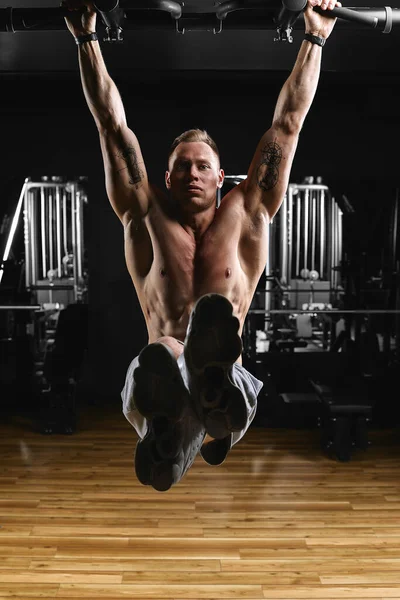 Güçlü bir adam kulaklı bir spor salonunda bir bar yapmak. — Stok fotoğraf