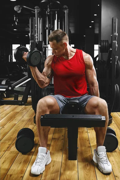 一名赤身裸体的肌肉男正在做二头肌运动，其中哑铃运动是他的健美运动的一部分。健康的动机，运动的生活方式，健康，运动的身体，积极的身体。薄膜颗粒 — 图库照片