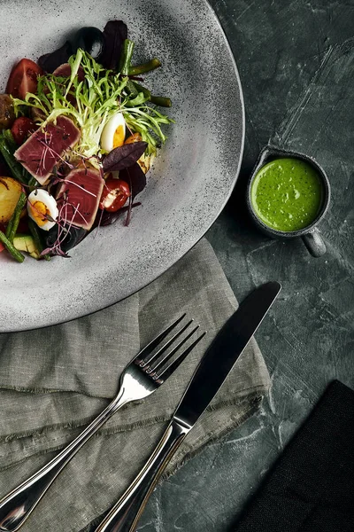 Nikoise-Salat mit Thunfisch auf einem grauen Teller, auf einem Serviertisch. Ein schönes Gericht vom Koch, Lebensmittel Foto, grauer Hintergrund, Kopierraum, traditionelle französische Küche. — Stockfoto