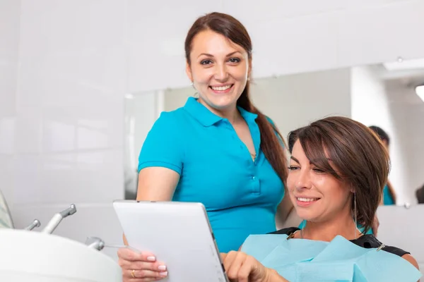 Portrait of a dentist discussing a treatment plan with a patient on a tablet