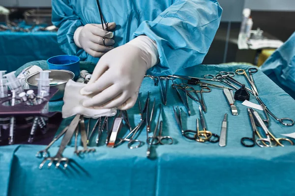 Chirurgische Instrumente im Operationssaal, die Assistentin arrangiert sie auf einem sterilen Takani. Das Konzept der Medizin, Chirurgie, sterilen Bereich. Plastische Chirurgie. Selektiver Fokus. — Stockfoto