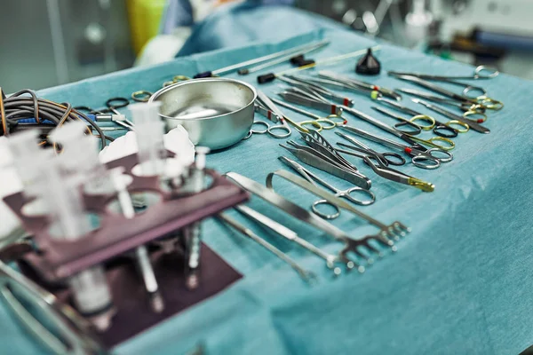 Instrumentos quirúrgicos en el quirófano, dispuestos sobre una mesa estéril sobre un tejido azul especial. El concepto de medicina, cirugía, área estéril. Cirugía plástica. Enfoque selectivo . — Foto de Stock