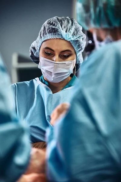 Στο χειρουργείο του νοσοκομείου. Μια διεθνής ομάδα επαγγελματιών χειρουργών και βοηθών εργάζεται σε ένα σύγχρονο χειρουργείο. Επαγγελματίες γιατροί γιορτάζουν έσωσε με επιτυχία ζωές. — Φωτογραφία Αρχείου