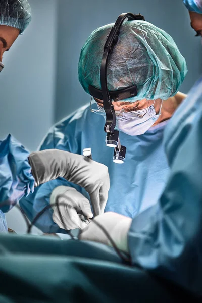 En el quirófano del hospital. Un equipo internacional de cirujanos y asistentes profesionales trabaja en un moderno quirófano. Médicos profesionales celebran vidas salvadas con éxito . — Foto de Stock