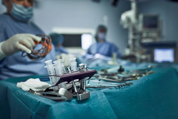 Sebészeti műszerek a műtőben, a sebész asszisztens intézi őket egy steril takanin. Az orvostudomány, a sebészet, a steril terület. Plasztikai sebészet. Szelektív fókusz. — Stock Fotó