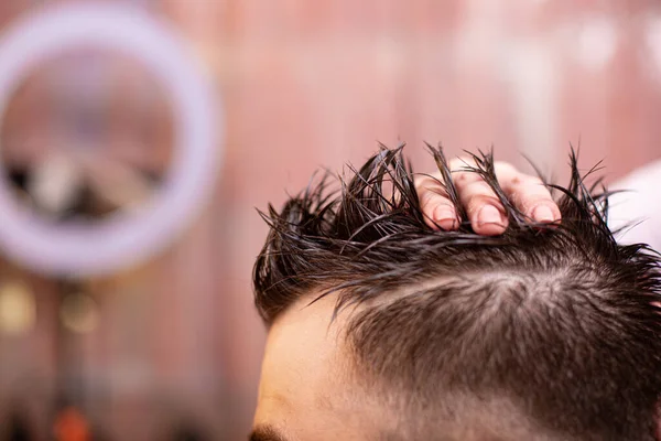 Mistr dává vlasy muže v holičství, kadeřník dělá účes pro mladého muže s pomocí gelu a laku. — Stock fotografie