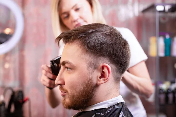 Nahaufnahme mit Haarschnitt. Hände, die einen Haarschneider halten. Friseur, Stilgestaltung, Schönheit. Schönheitssalon. — Stockfoto