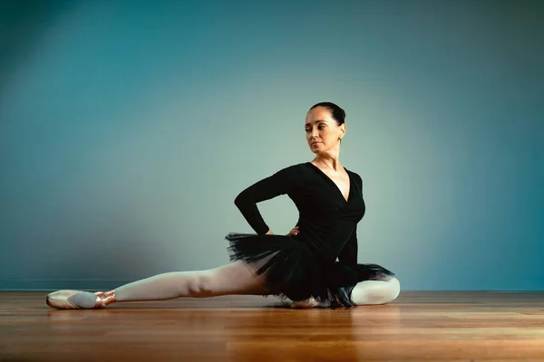 Mujer hermosa adulta 45-55 años, bailarina en zapatos puntiagudos se sienta en el suelo y posa para la cámara. La vejez activa, el conocimiento de la vida. Entrenador de ballet de edad . — Foto de Stock