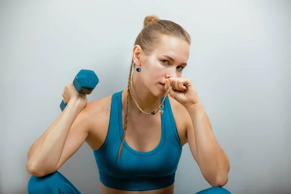 Hermoso modelo de fitness haciendo ejercicios con mancuernas en las manos sobre un fondo gris. Primer plano. Mujer posando en cámara con pesas. Estilo de vida saludable. Lograr metas, motivación deportiva. Copiar espacio — Foto de Stock