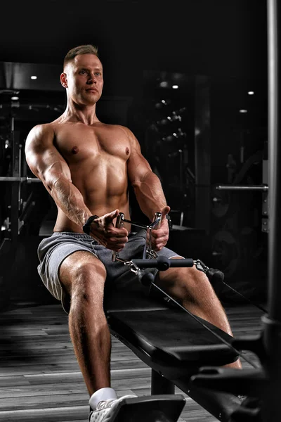 Guapo culturista haciendo ejercicio de peso pesado para la espalda en un simulador. Cuerpo atlético, preparación para la temporada de verano. Motivación física. Copiar espacio, banner deportivo —  Fotos de Stock