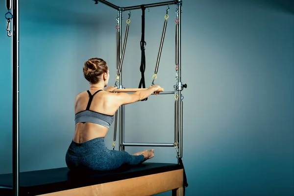 Jimnastikçi kadın, reformist yatak eğitmeni kızda esneme sporu yapıyor. Mavi arka plan, sağlıklı vücut, esneme hareketleri. Fitness konsepti — Stok fotoğraf