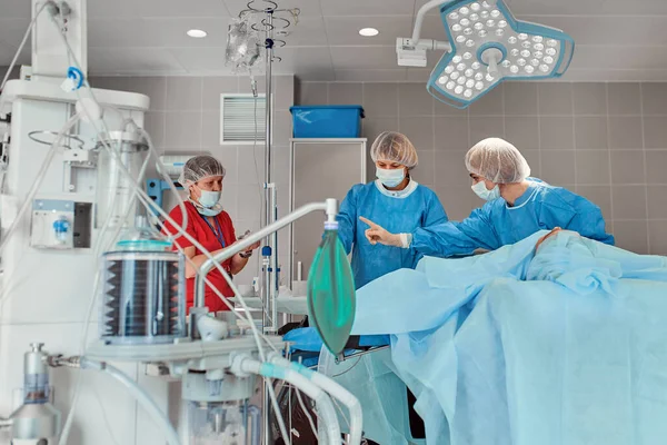 医者のチームが手術を行う。手術室で働く外科医のグループは、肺炎から患者の命を救う。ウイルスとの戦いだ。流行だポンデミア。コヴィト19 — ストック写真